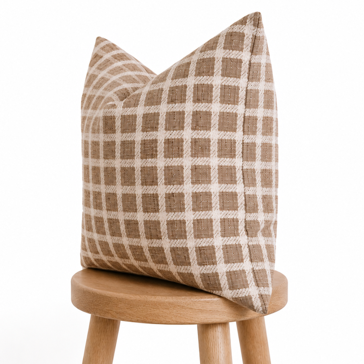 Plaid pillow on a wooden stool against a white background