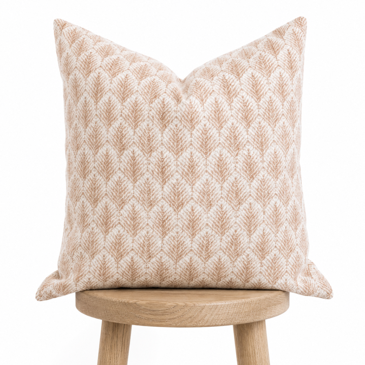 Decorative pillow with a geometric pattern on a wooden stool against a white background