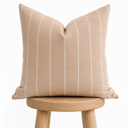 Beige striped pillow on a wooden stool against a white background
