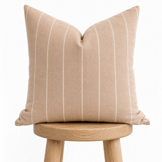 Beige striped pillow on a wooden stool against a white background