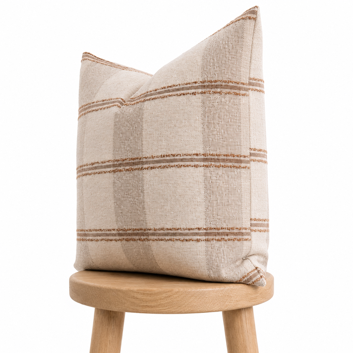 Textured pillow on a wooden stool against a white background